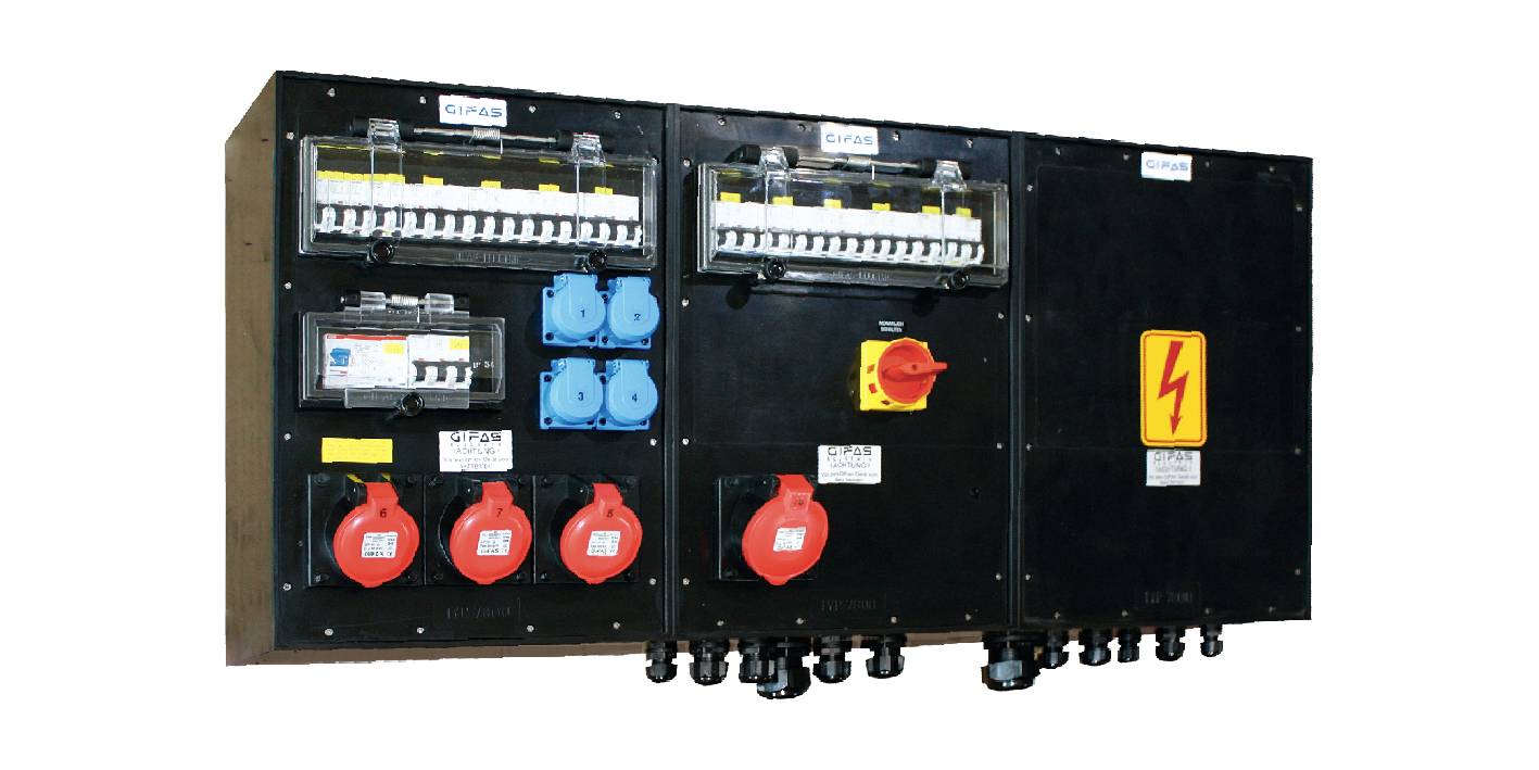 Pannello di distribuzione elettrica con interruttori automatici, prese blu e rosse, e un cartello di avvertimento ad alta tensione giallo.