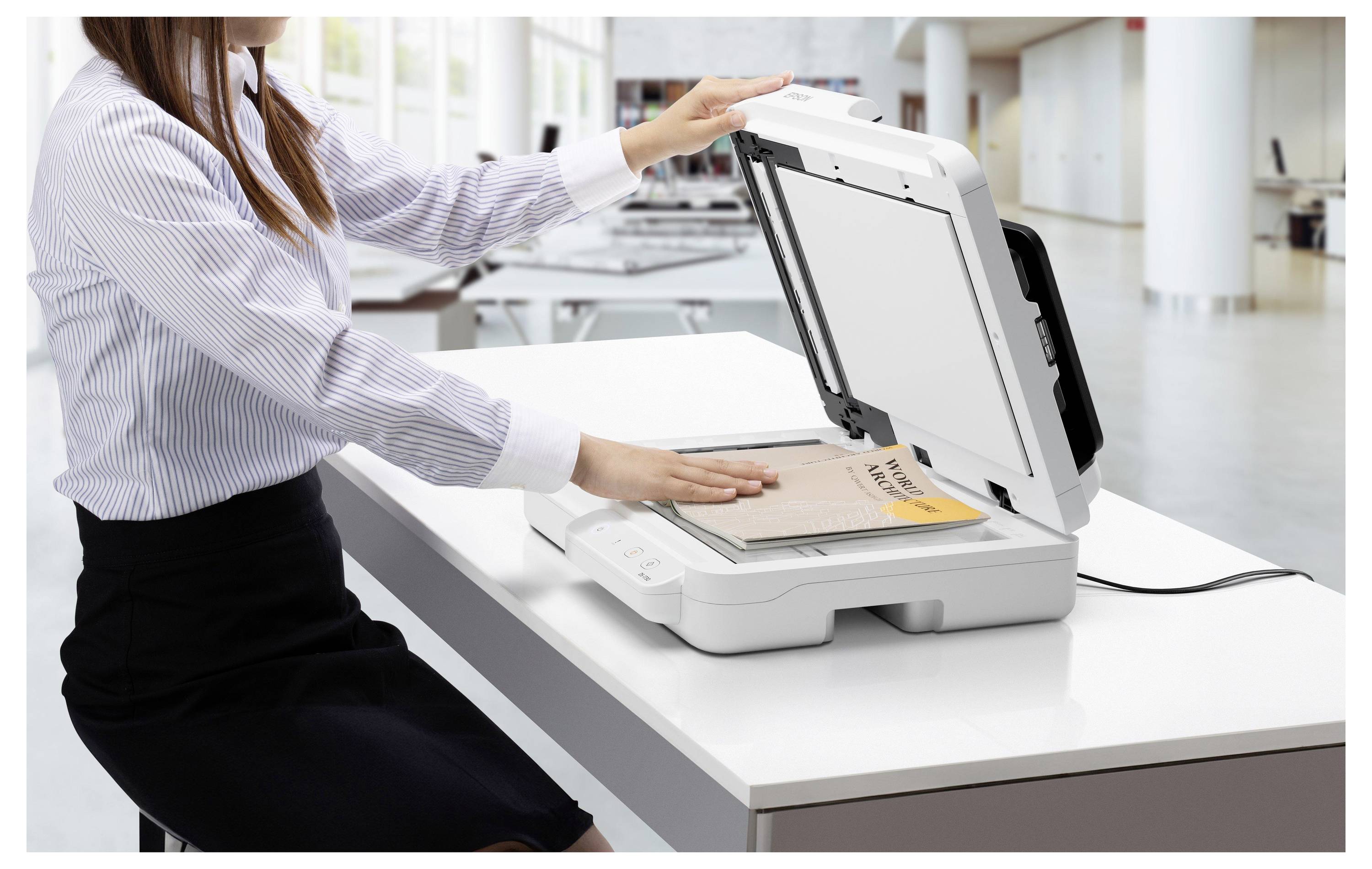 Donna che utilizza uno scanner a letto piano per scansionare documenti su una scrivania in un ufficio luminoso.