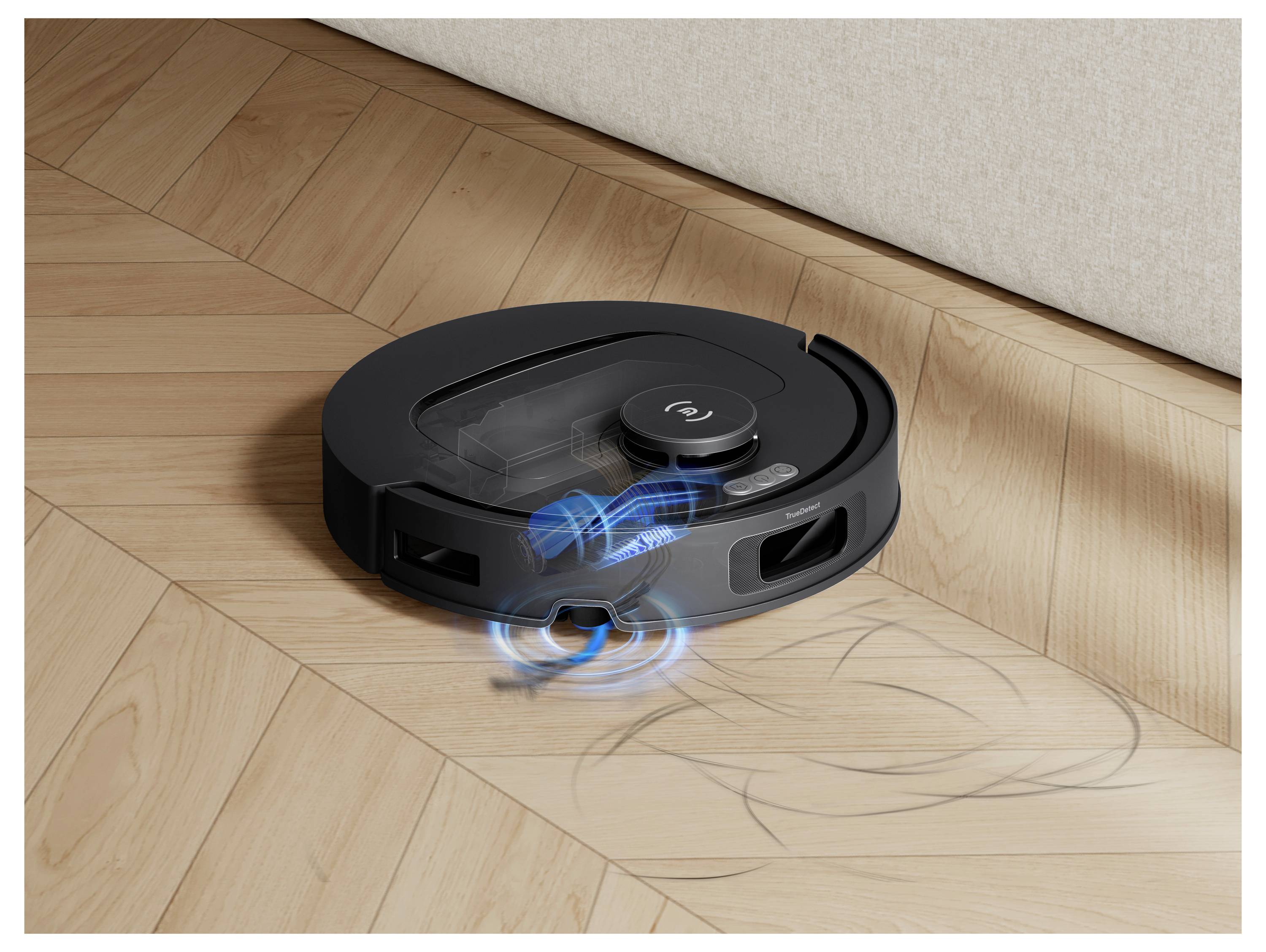 Robot aspirapolvere nero che pulisce un pavimento in legno duro vicino a un muro, con linee di movimento blu che indicano l'aspirazione attiva e l'azione della spazzola laterale.