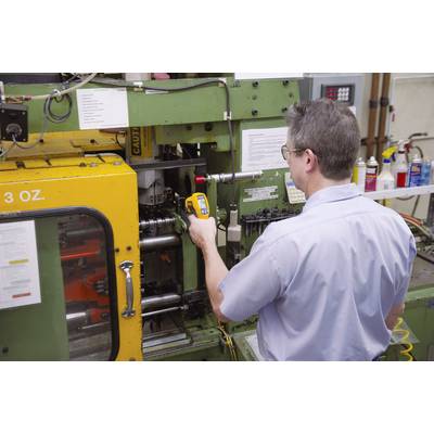 Un uomo sta azionando una grande macchina industriale in una fabbrica. Sta utilizzando uno strumento di misurazione per eseguire un controllo.