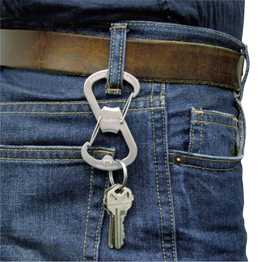 Un mazzo di chiavi con due chiavi pende da un moschettone argentato, fissato a un passante di una cintura in pelle marrone.