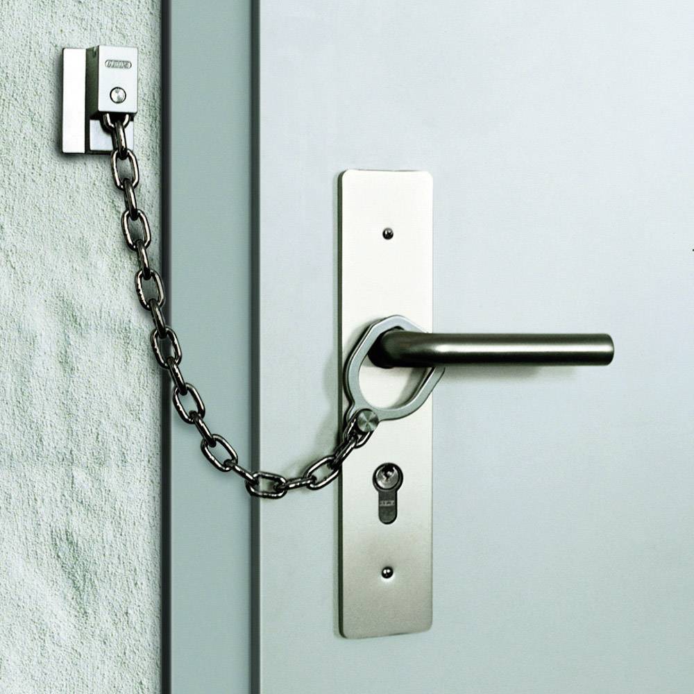 Porta con maniglia argentata e catena come ulteriore sicurezza. La catena collega la porta al telaio e offre protezione contro l'apertura involontaria.
