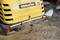 Un piccolo escavatore giallo con la scritta 'Komatsu' e 'Giardinaggio e sistemazione paesaggistica' sullo sfondo. Una pala è poggiata sul retro.