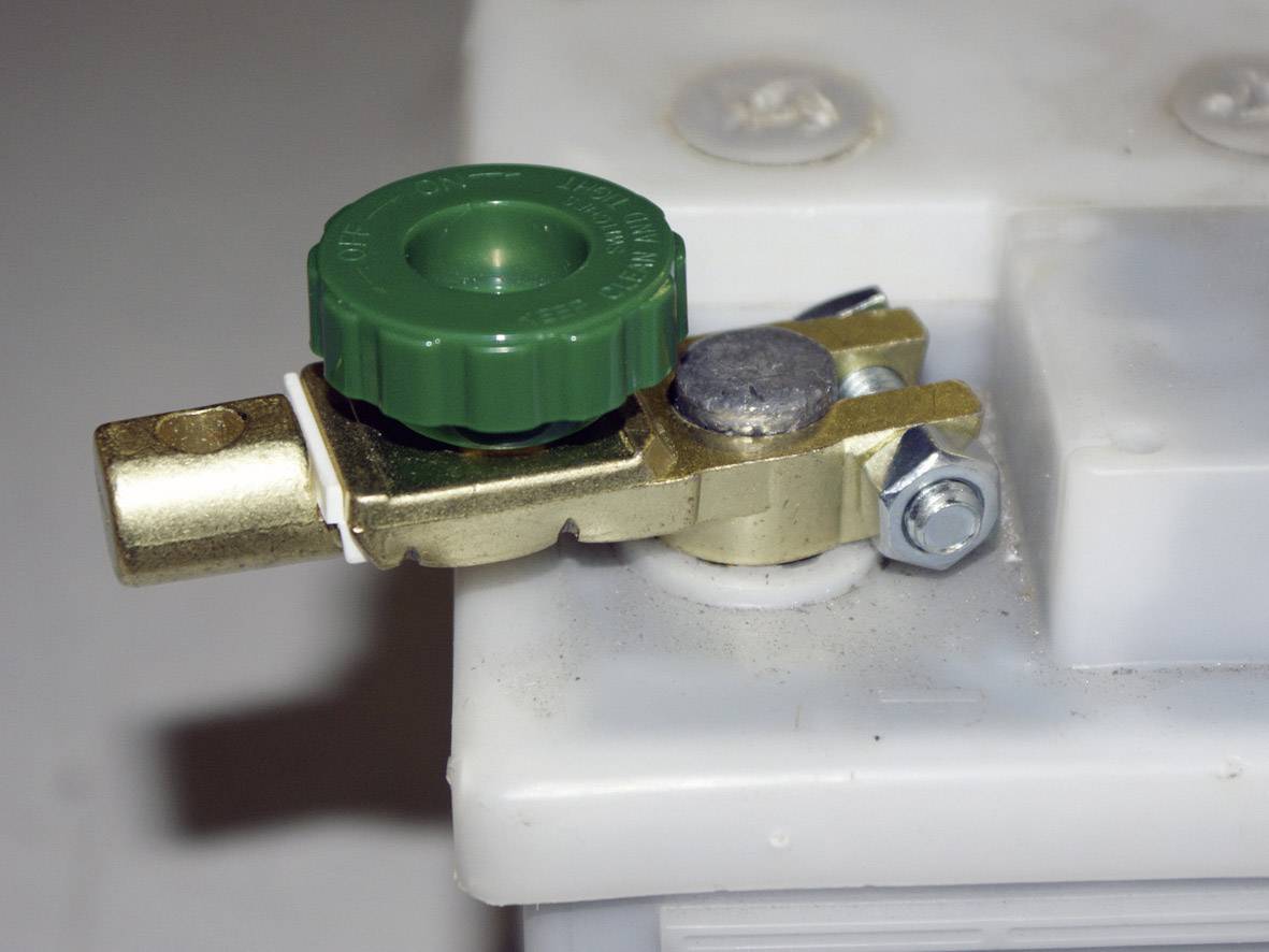 Un interruttore verde per morsetti della batteria su una batteria automobilistica bianca.