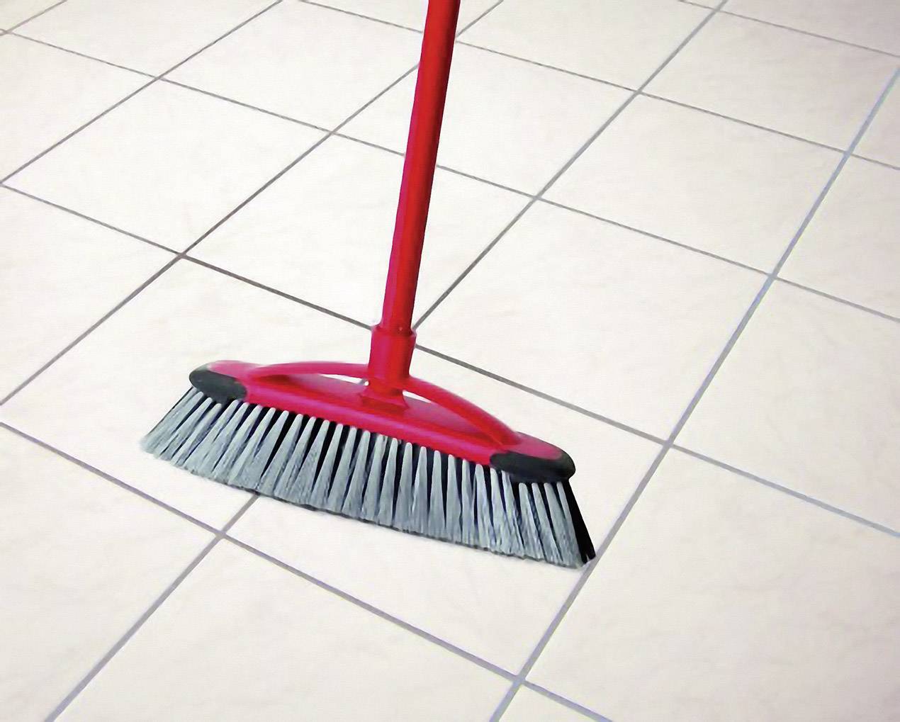 Una scopa rossa spazza su un pavimento piastrellato che sembra pulito.