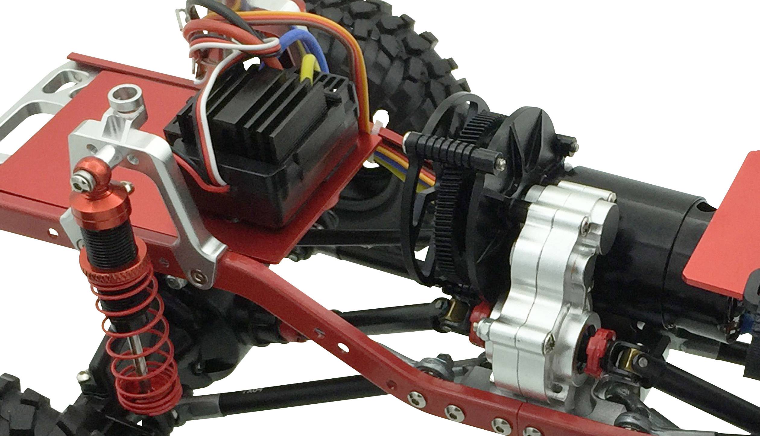 Un primo piano di un modello di auto radiocomandata mostra la sospensione, i componenti del motore e il cablaggio su un telaio rosso.