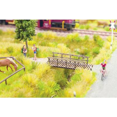 Una scena in miniatura mostra due escursionisti vicino a un albero, un cavallo al pascolo e una persona in bicicletta accanto a un piccolo ponte di legno. Sullo sfondo passa un treno.