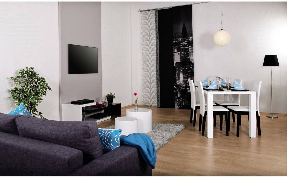 Soggiorno moderno con divano grigio, tavolo da pranzo per quattro persone e lampada a sospensione, decorazione elegante con pianta e arte parietale.