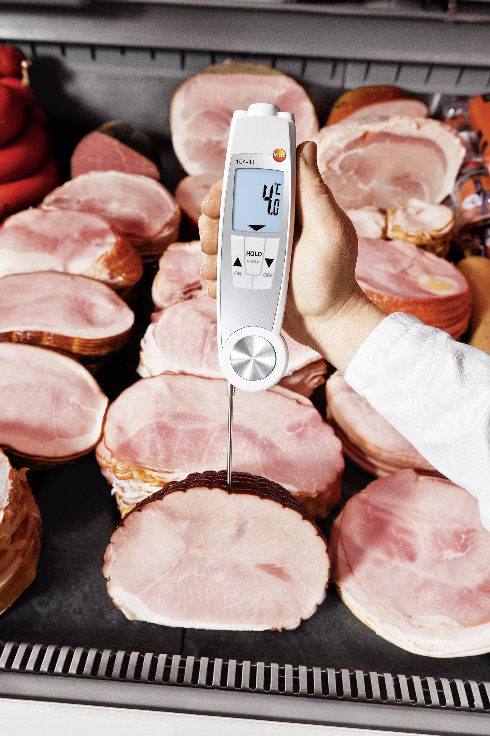 Una mano tiene un termometro in un pezzo di prosciutto tagliato. Il display mostra 41,3 gradi Celsius.