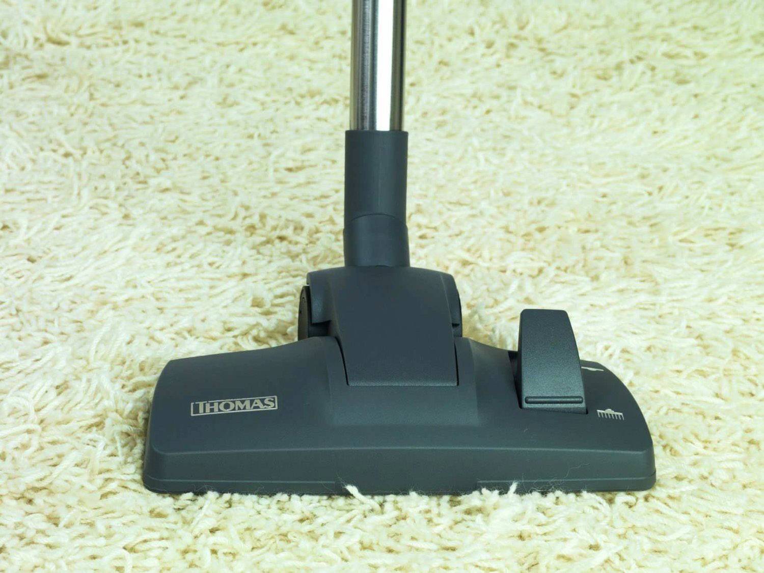 Un aspirapolvere con testa nera su un tappeto beige chiaro. La caratteristica principale è la facilità di utilizzo e la pulizia efficiente.