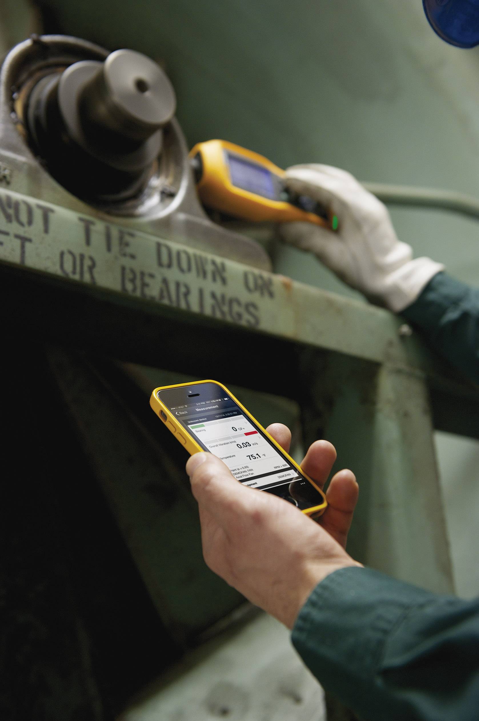 Una persona sta controllando lo stato di una grande macchina utilizzando un dispositivo mobile e uno smartphone.