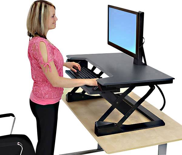 Una donna lavora davanti a un monitor, in piedi presso una scrivania regolabile in altezza.