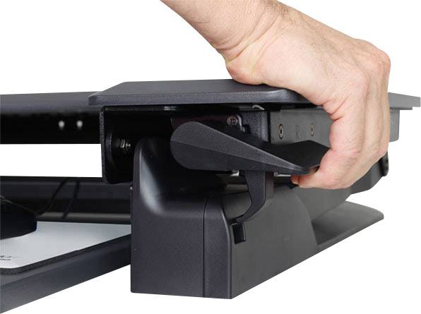 Una mano regola l'altezza di un supporto da tavolo premendo una leva, mostrando un'impostazione ergonomica.