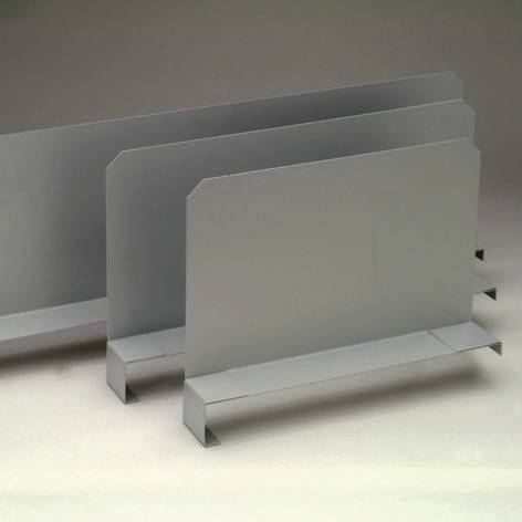 Tre porta riviste metallici grigio-argentati di dimensioni diverse sono disposti uno accanto all'altro su una superficie grigia.