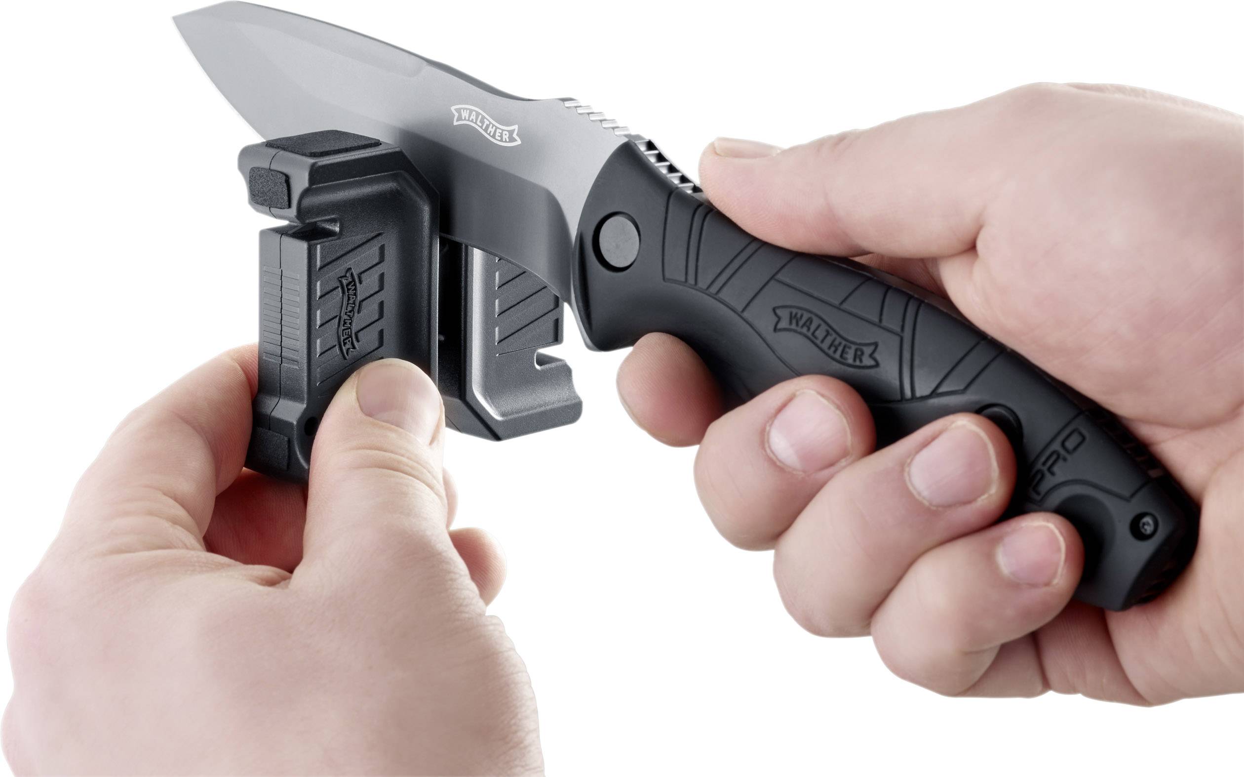 Una mano tiene un coltello tascabile nero, mentre l'altra mano usa uno strumento per affilare la lama.