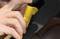 Una persona tiene un tagliagurta di sicurezza giallo e taglia la cintura di sicurezza all'interno di un'auto.