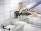 Una persona sta utilizzando un utensile multiuso elettrico per rimuovere il materiale sigillante tra le piastrelle bianche del bagno.