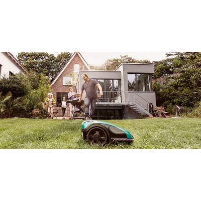 Una famiglia osserva un rasaerba automatico mentre si trova nel giardino di una casa moderna.