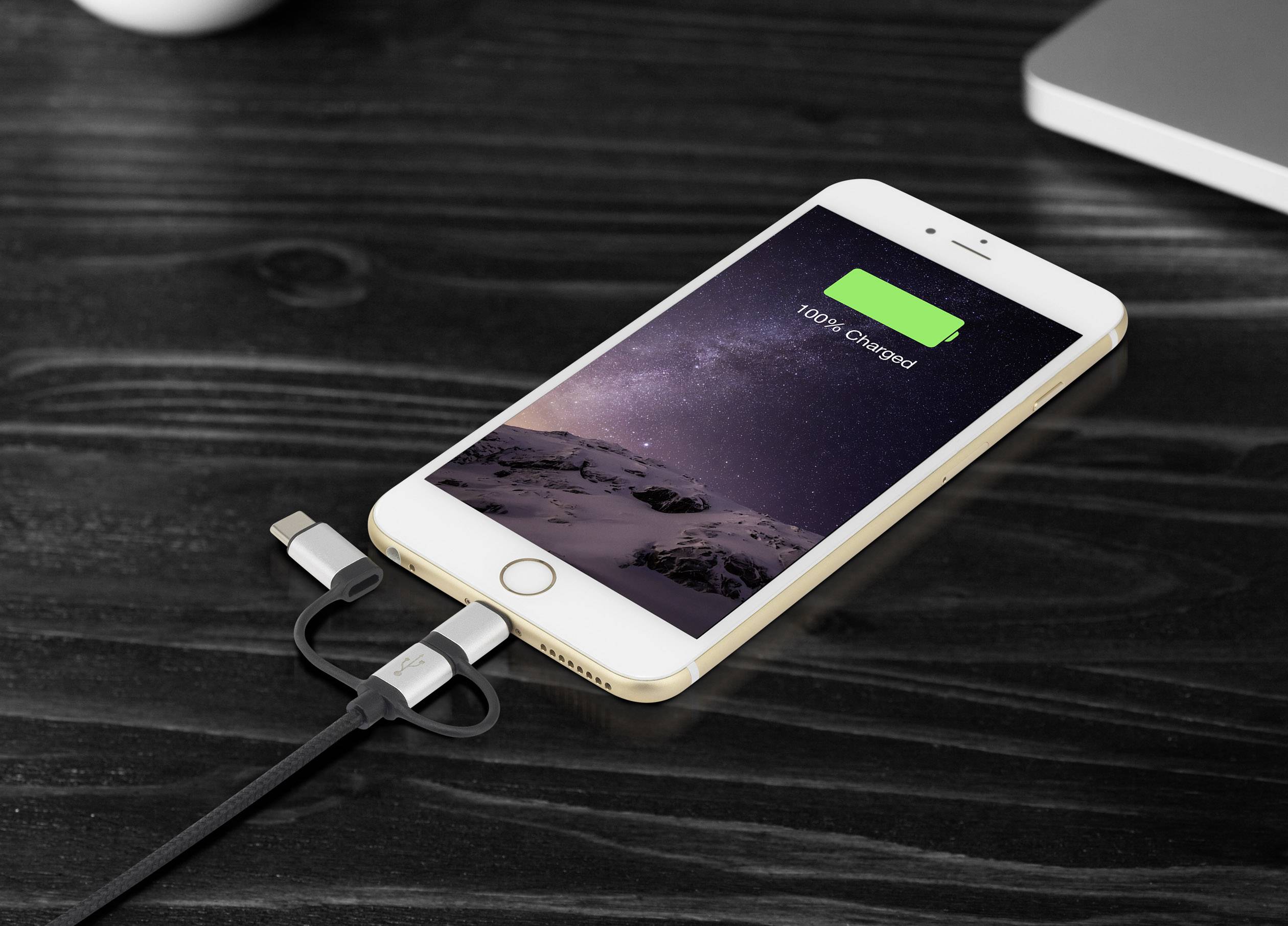 Un smartphone è poggiato su un tavolo e sta caricando. Lo schermo mostra '100% carico'.