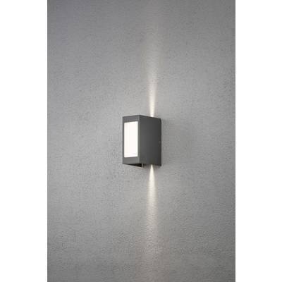 Applique da parete con paralume rettangolare che diffonde la luce sia verso l'alto che verso il basso su una parete grigia.