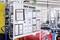 Un pannello informativo in un capannone industriale mostra diagrammi e istruzioni per la sicurezza e l'efficienza sul luogo di lavoro. Sullo sfondo sono visibili delle macchine.