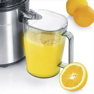 Un estrattore elettrico accanto a un boccale pieno di succo d'arancia, con due arance intere e un'arancia tagliata a metà poggiate vicino.