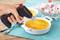 Mano tiene un bruciatore per fiammeggiare sopra una coppetta di crème brûlée, accanto a una ciotola con cubetti spolverati di zucchero a velo.