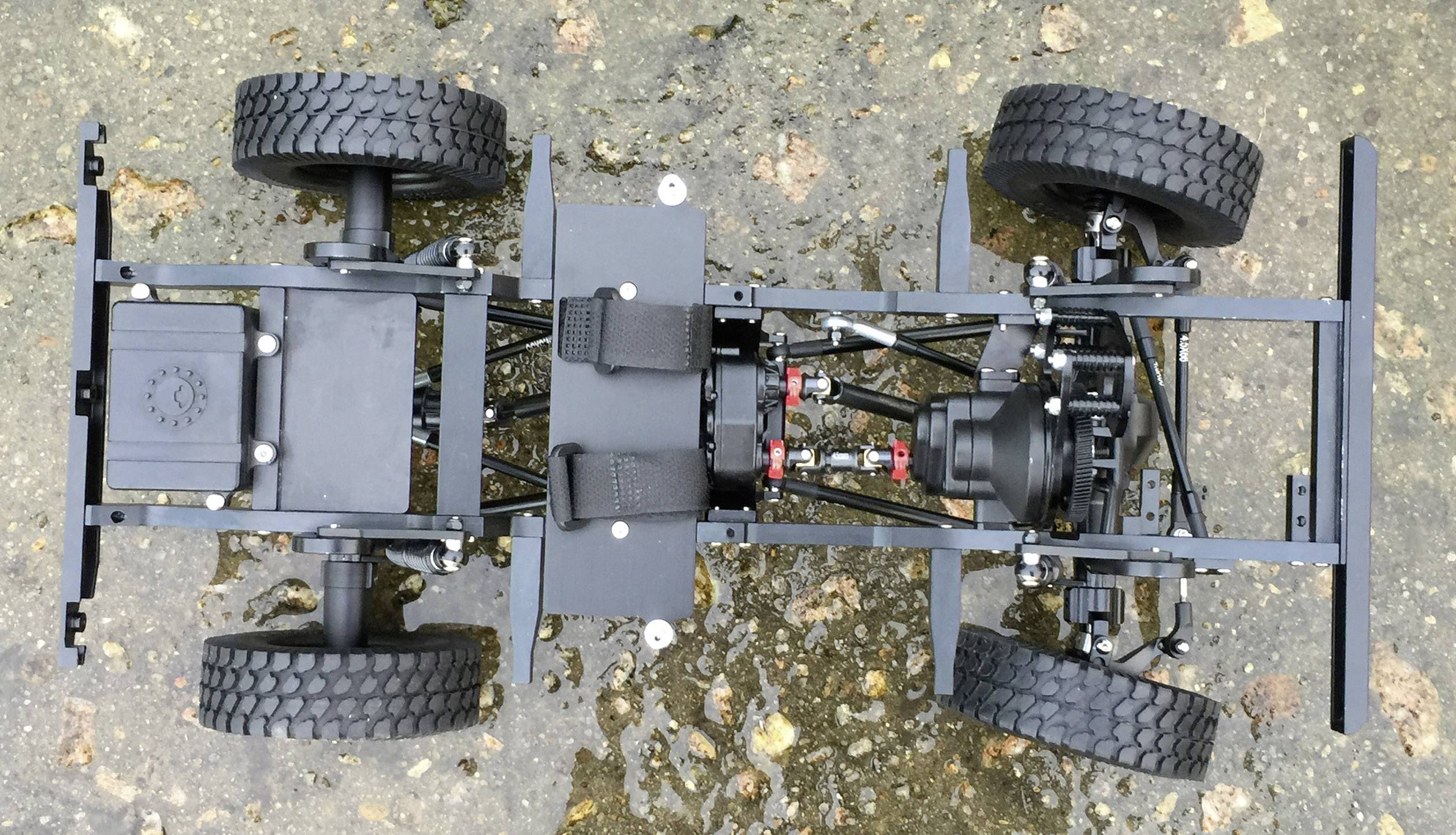 Vista dall'alto di un modello di telaio RC, mostra il sistema di trasmissione, la sospensione e quattro pneumatici robusti. Progetto di costruzione di veicoli.