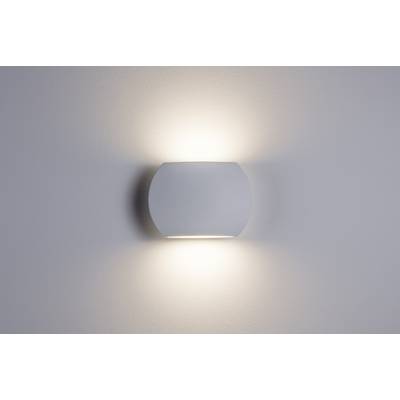 Un moderno applique emana luce diffusa verso l'alto e verso il basso, garantendo un'illuminazione soffice su una parete bianca e liscia.