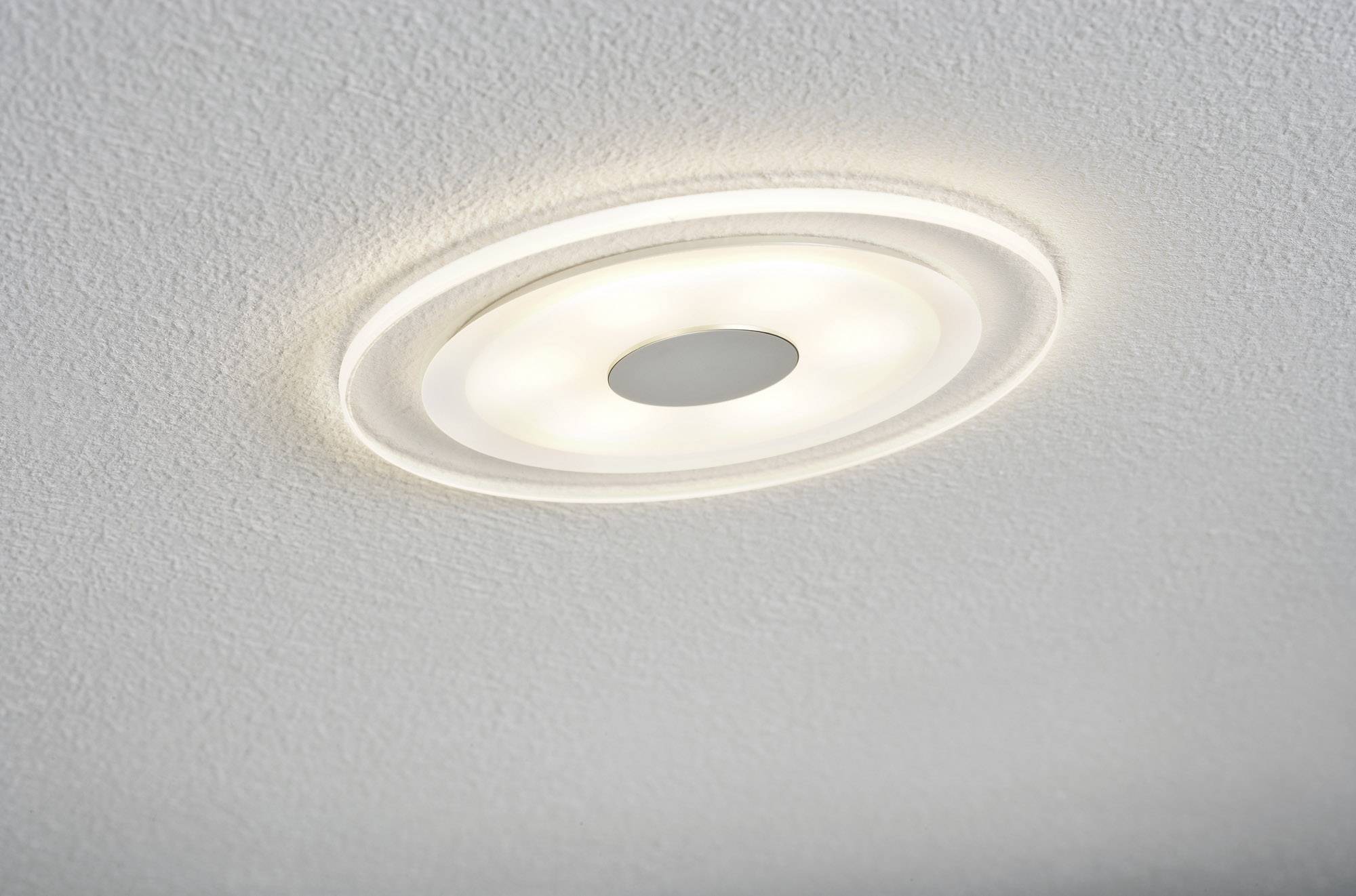 Plafoniera rotonda e moderna, incassata in un soffitto bianco. Illumina e garantisce un'illuminazione uniforme.