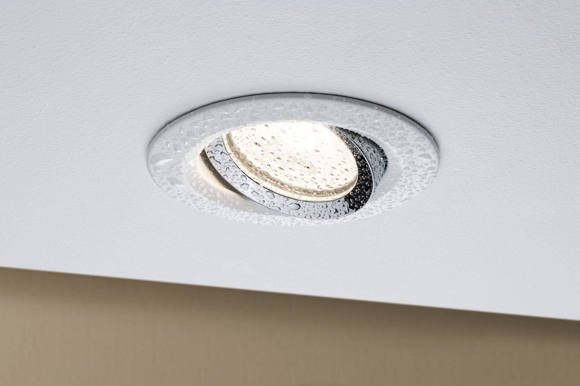 Una plafoniera bianca da incasso nel soffitto, illuminata con lampadina a vista e leggero vapore acqueo attorno al bordo.