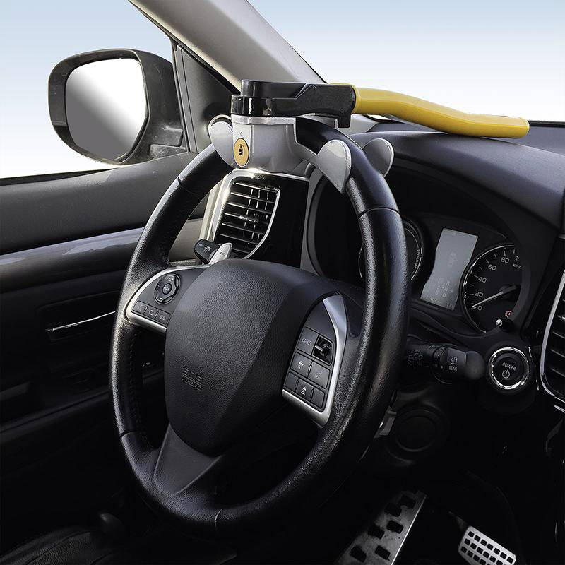 Un dispositivo antifurto a clava è montato sul volante di un'auto per prevenire il furto. È giallo e nero e blocca lo sterzo.