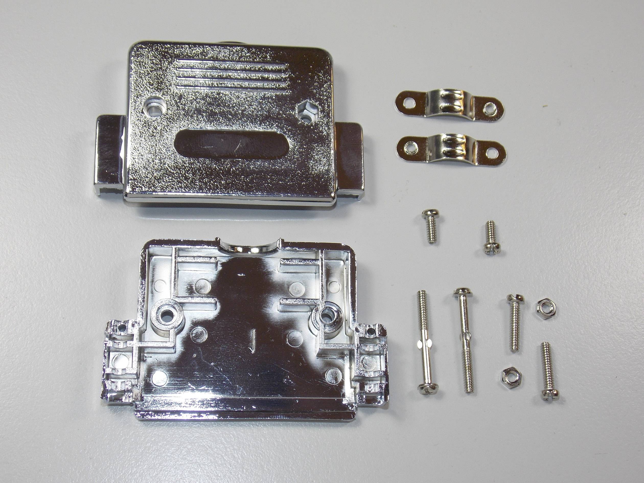 Involucro di connettore metallico, con lato anteriore e posteriore aperti. Accanto a questo, quattro viti e due supporti. Tutti i componenti sono di colore argento.