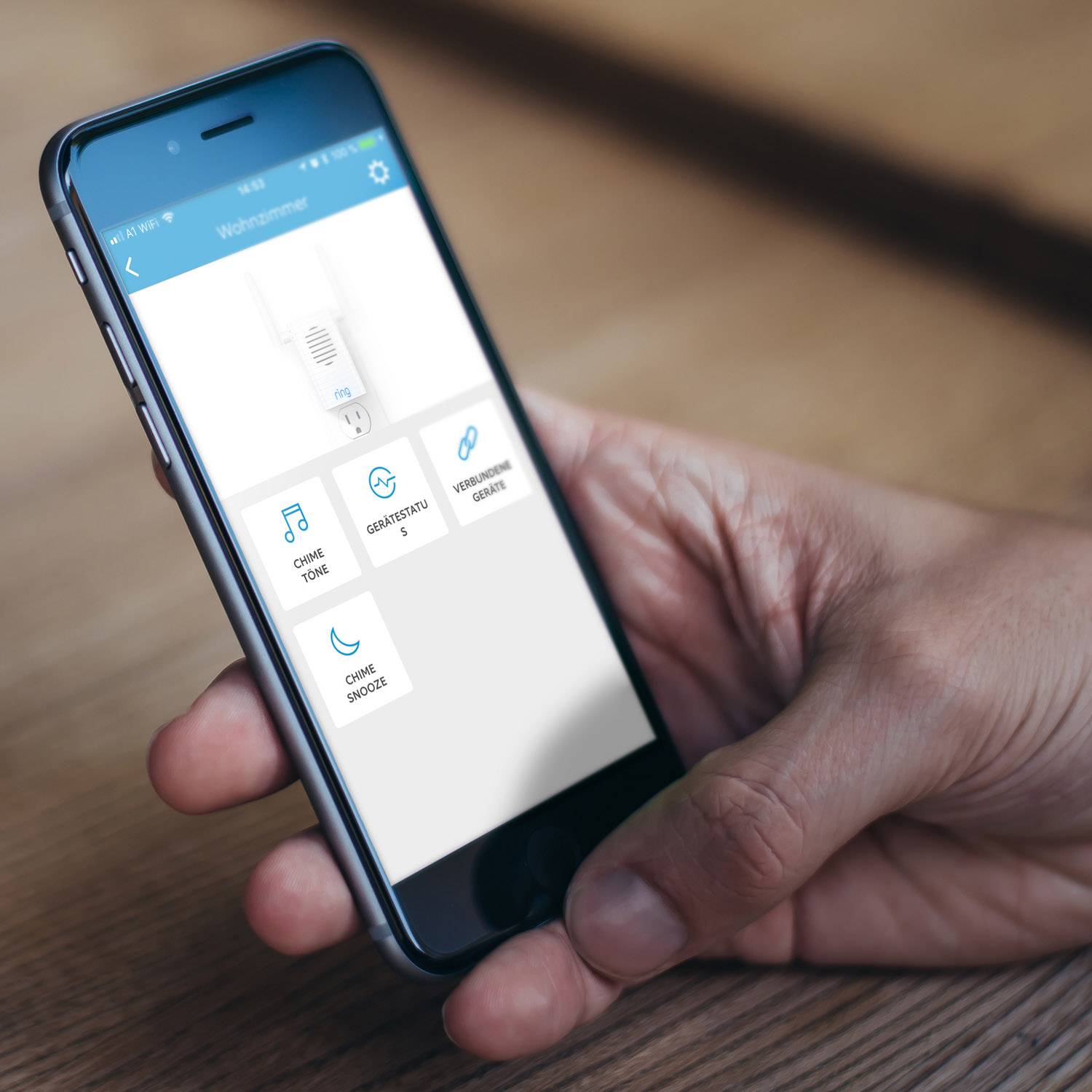 Uno smartphone viene tenuto in una mano. Sul display è visualizzata un'app per la casa intelligente con opzioni per 'Suoni', 'Dispositivi' e 'Sicurezza'.