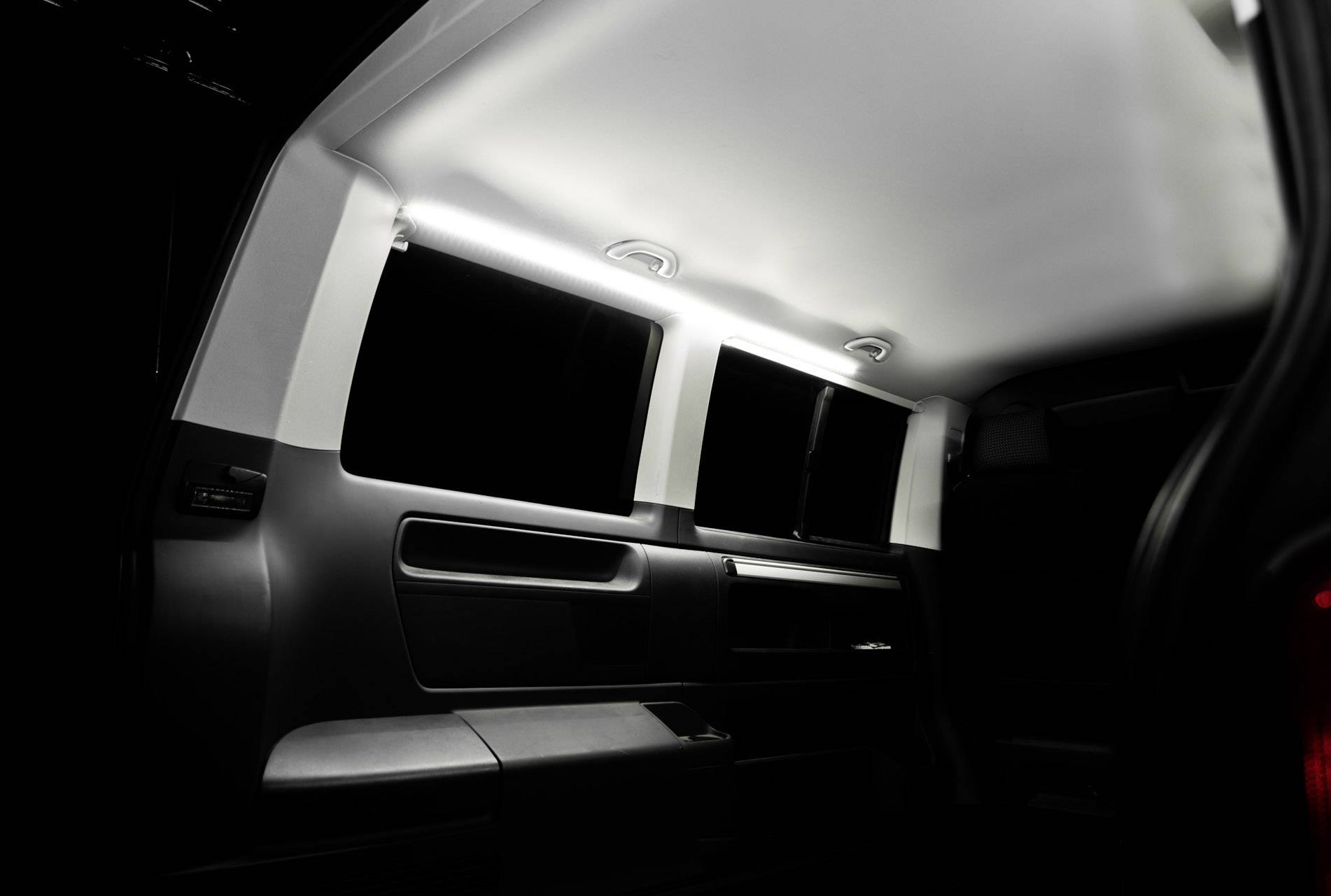 Vista posteriore dell'interno di un veicolo con illuminazione soffusa, linee dei finestrini nitide, rivestimenti interni scuri e design moderno.