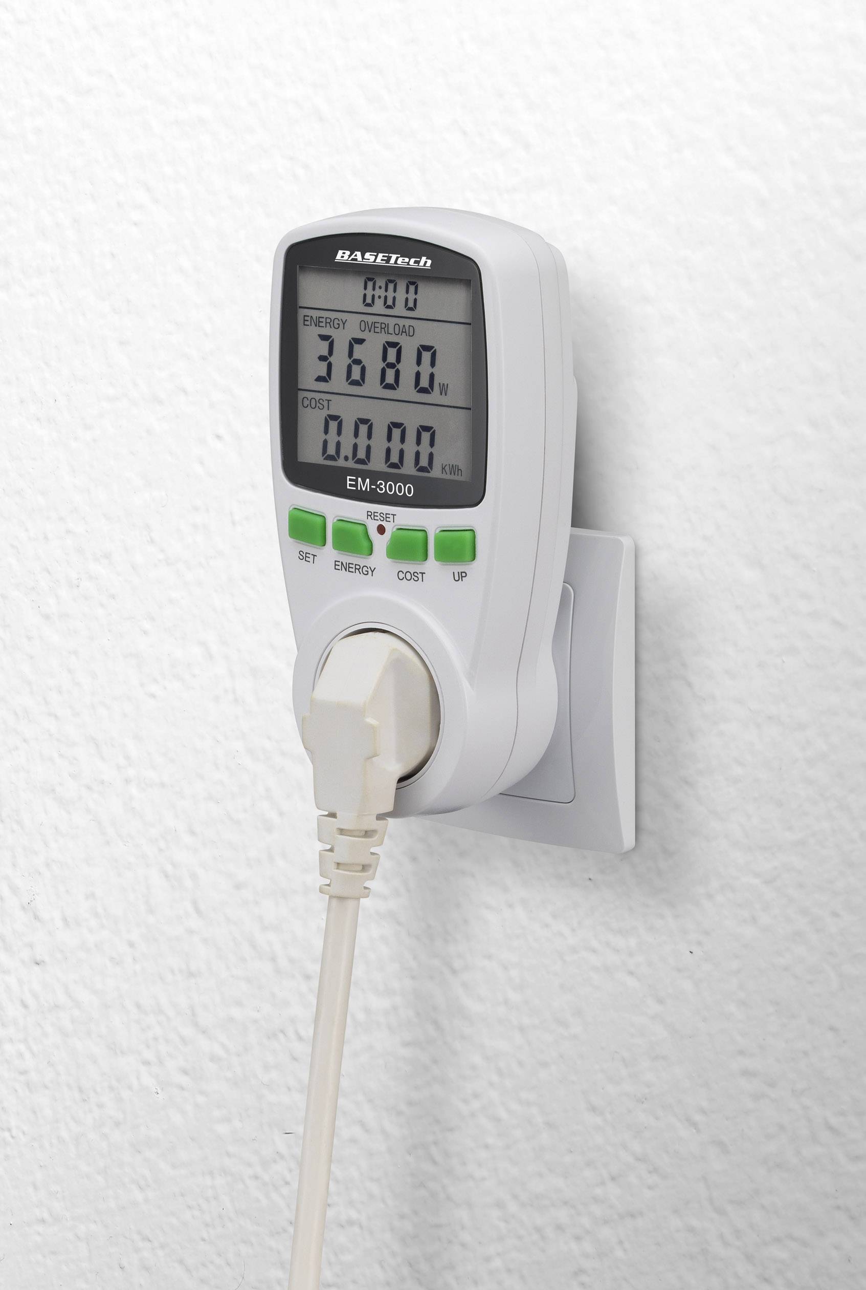 Un misuratore di energia è collegato a una presa elettrica, mostra i valori di consumo su un display digitale e ha un bordo bianco.