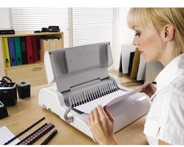 Una persona sta allegando un documento a una scrivania. Sullo sfondo si vedono cartelle colorate e accessori da ufficio.
