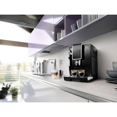 Una macchina da caffè nera su un bancone della cucina sta preparando due espressi. Accanto c'è un latte macchiato e alcune stoviglie.
