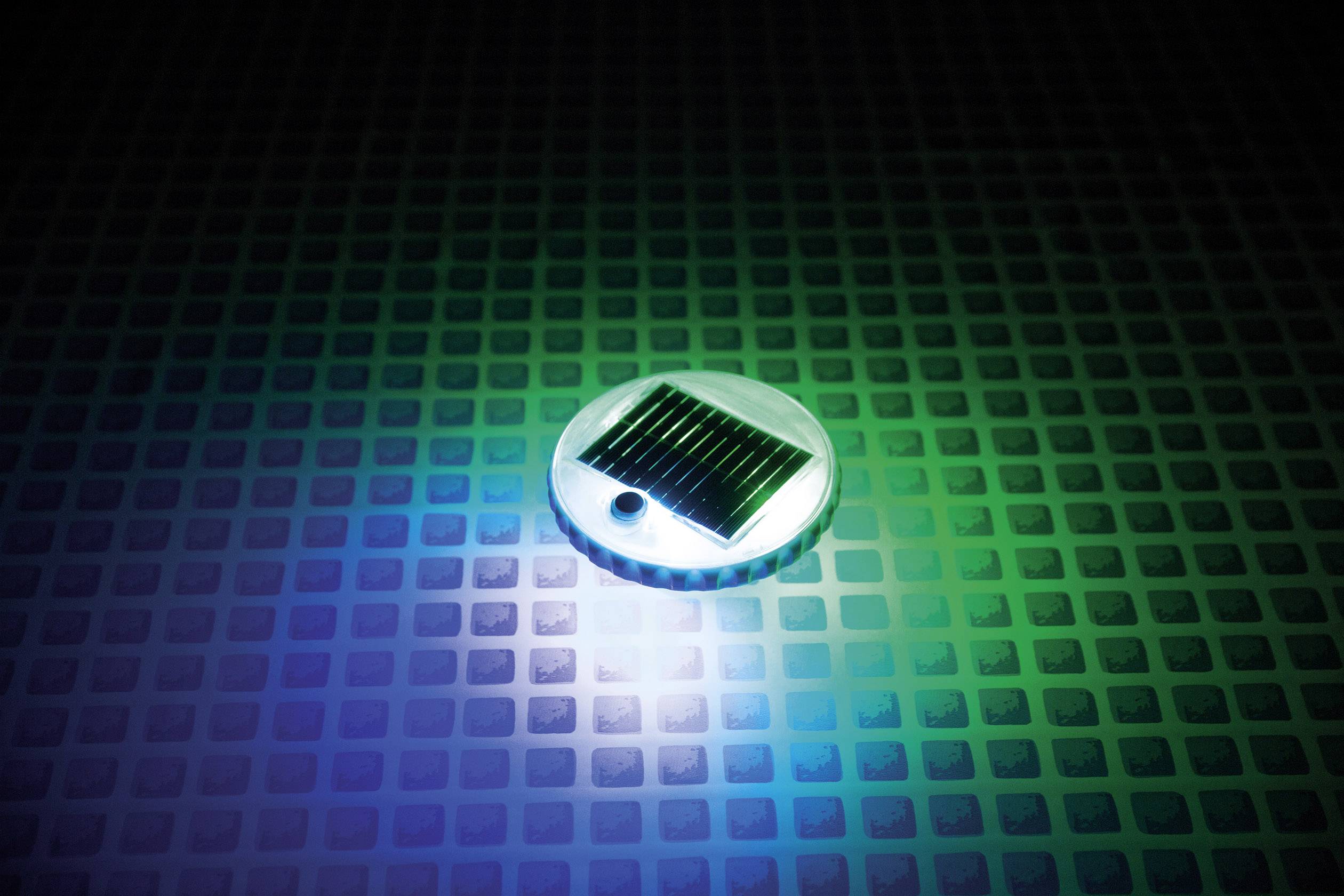 Una piccola batteria solare giace su una superficie illuminata, con sfumature di colore.