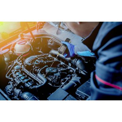 Un meccanico controlla il motore di un'auto con un dispositivo diagnostico. Il vano motore è chiaramente visibile, con l'attenzione concentrata sulla diagnosi.