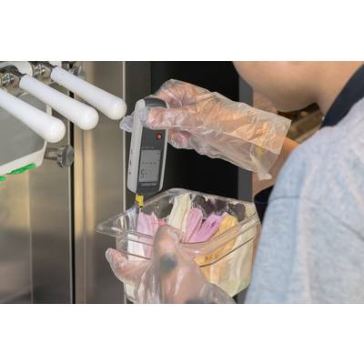 Una persona misura la temperatura del gelato in un contenitore utilizzando un termometro digitale.