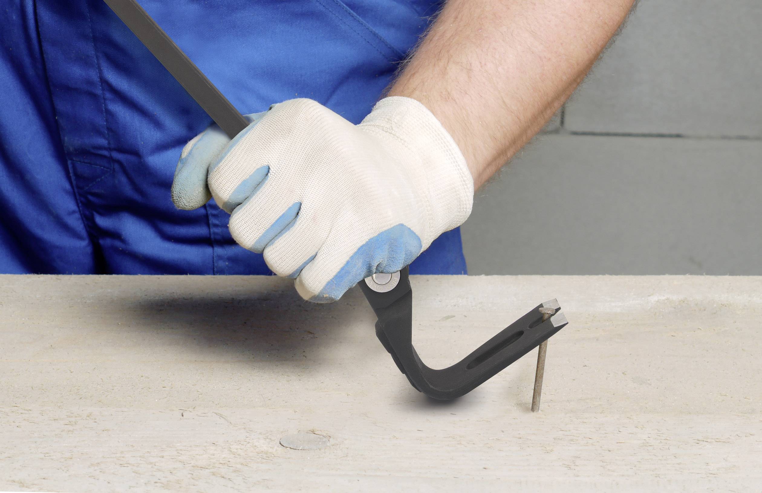 Una persona con indumenti da lavoro blu sta rimuovendo un chiodo da un'asse di legno usando una levetta.