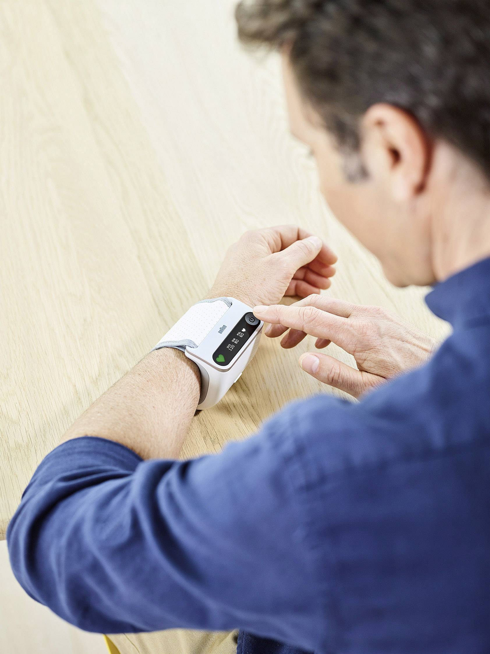 Una persona indossa un braccialetto fitness, tocca il display che mostra dati sulla salute. Focus sulla tecnologia in uso.