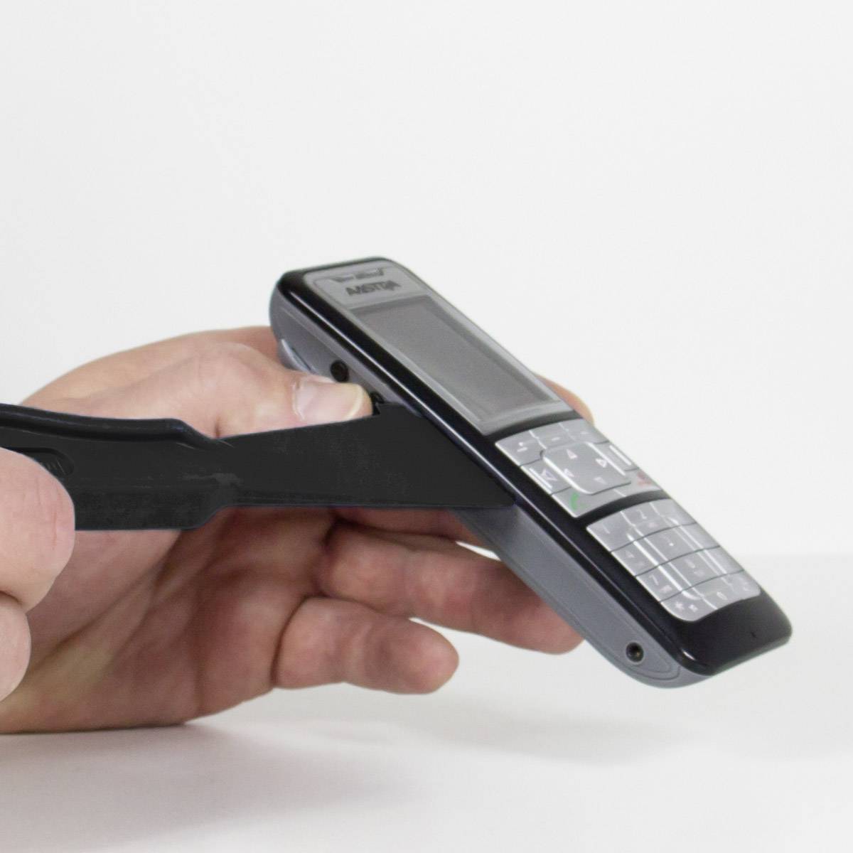 Una persona tiene in mano un telefono cellulare e lo apre con un attrezzo nero.