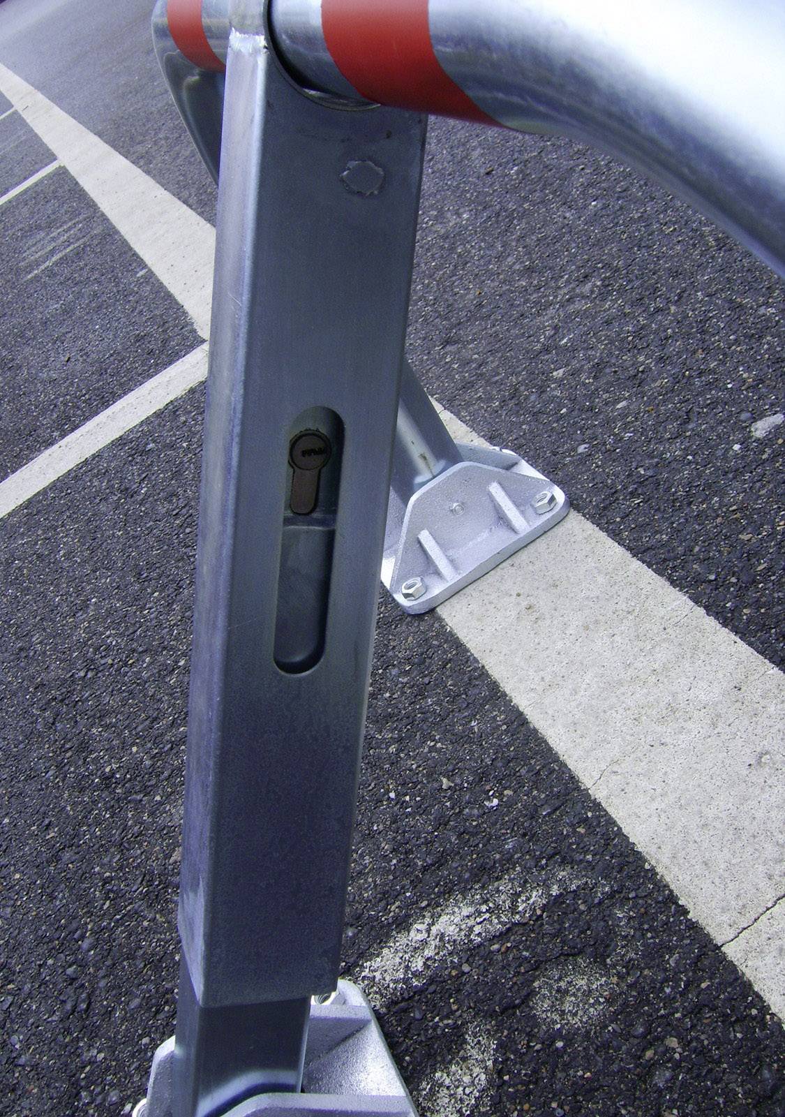 Un paletto mobile di delimitazione su una strada, fissato con un lucchetto, serve a regolare l'accesso o la sosta.