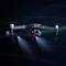 Un drone vola, circondato da uno sfondo scuro. Le sue luci sono accese, trasmettendo un'impressione tecnologica e futuristica.