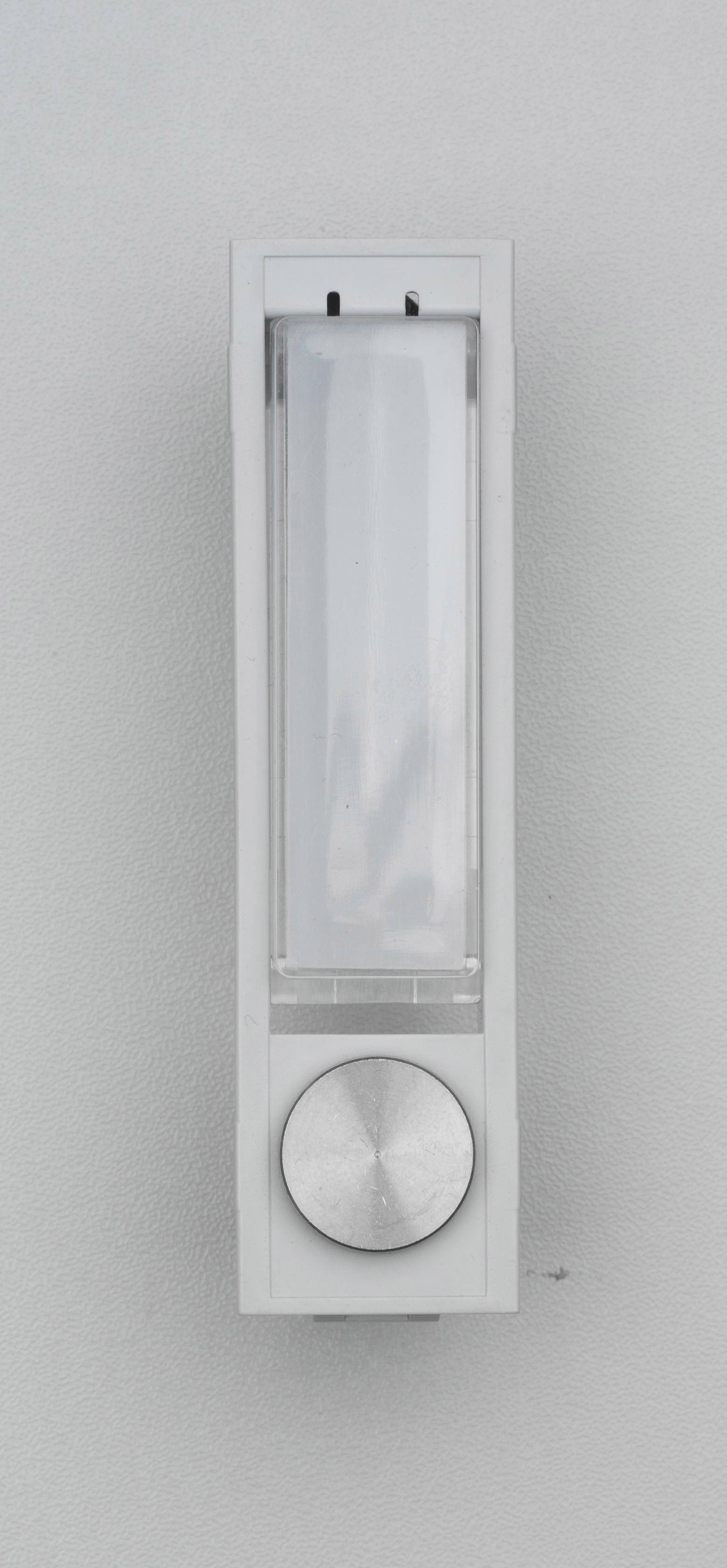 Interruttore luce bianco dal design rettangolare con una manopola rotonda sottostante, fissato a una parete grigia.
