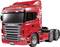 Camion Scania rosso, modello 'Highline' con un design accattivante, percorre una strada. Logo distintivo del marchio sul lato del veicolo.