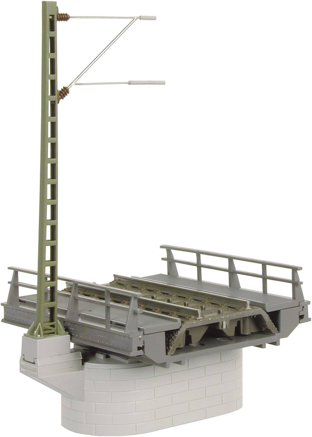 Un modello di ponte ferroviario con linea verde e binari grigi su un piedistallo grigio e rotondo.
