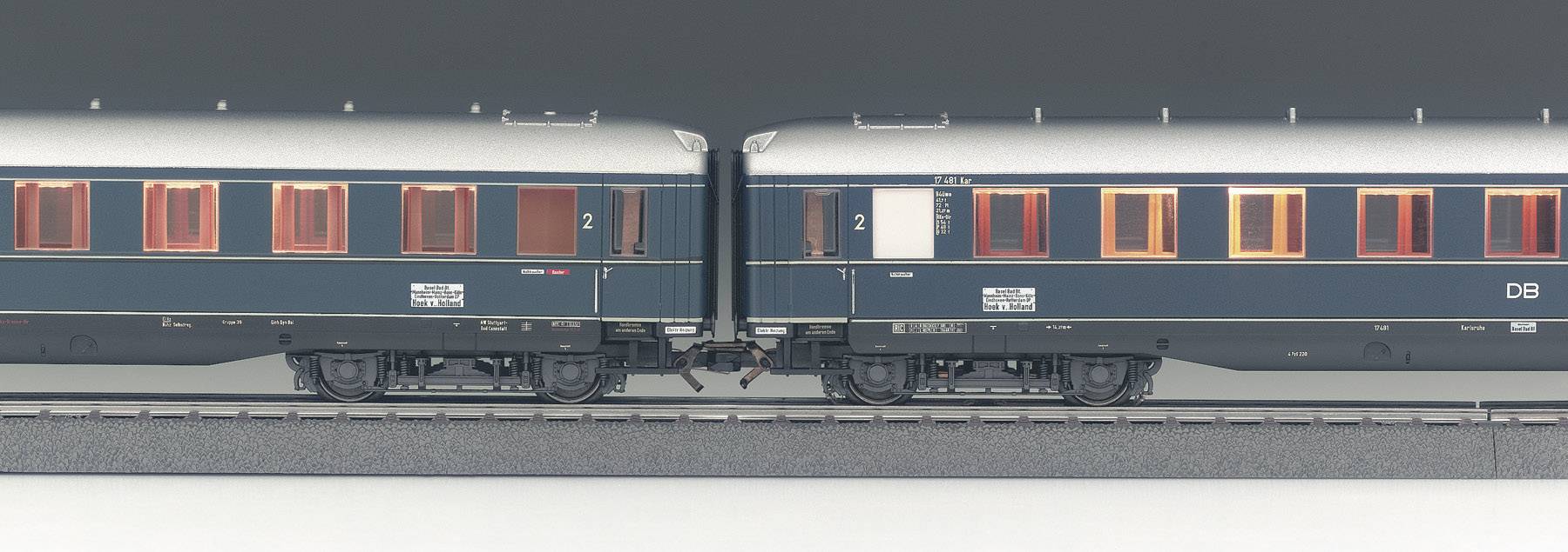 Due vagoni ferroviari blu, collegati su un binario, con finestre che brillano di arancione.
